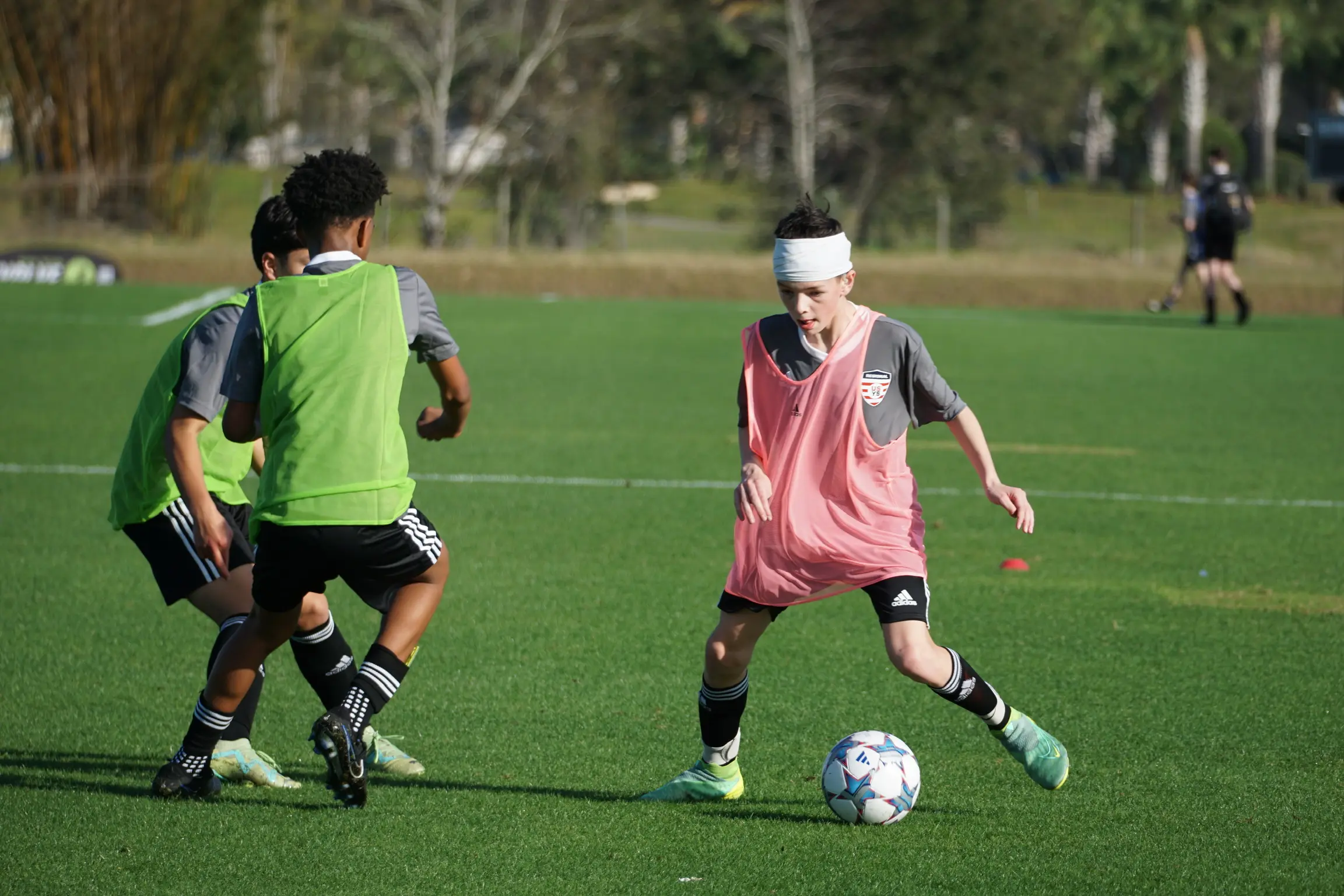 Daylen Hammon in black ODP kit with white headband battling green-kitted defender at ODP Regionals Orlando FL January 2024